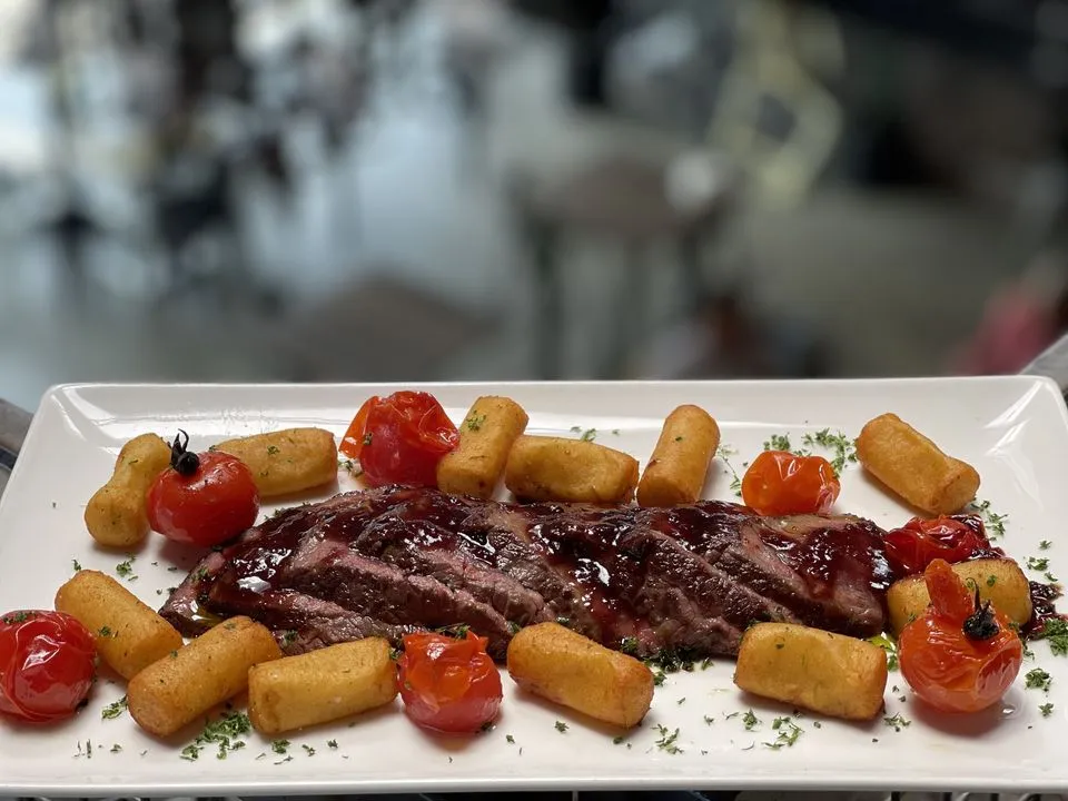 Tagliatta de wapiti avec jus de viande aux fruits rouges, croquettes de pommes de terre et tomates cerises rôties.