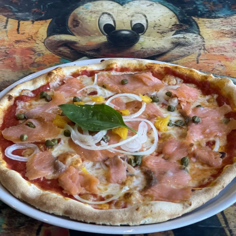 Pizza tomate, mozzarella, saumon fumé, oignons, câpres, petits suprêmes d'orange